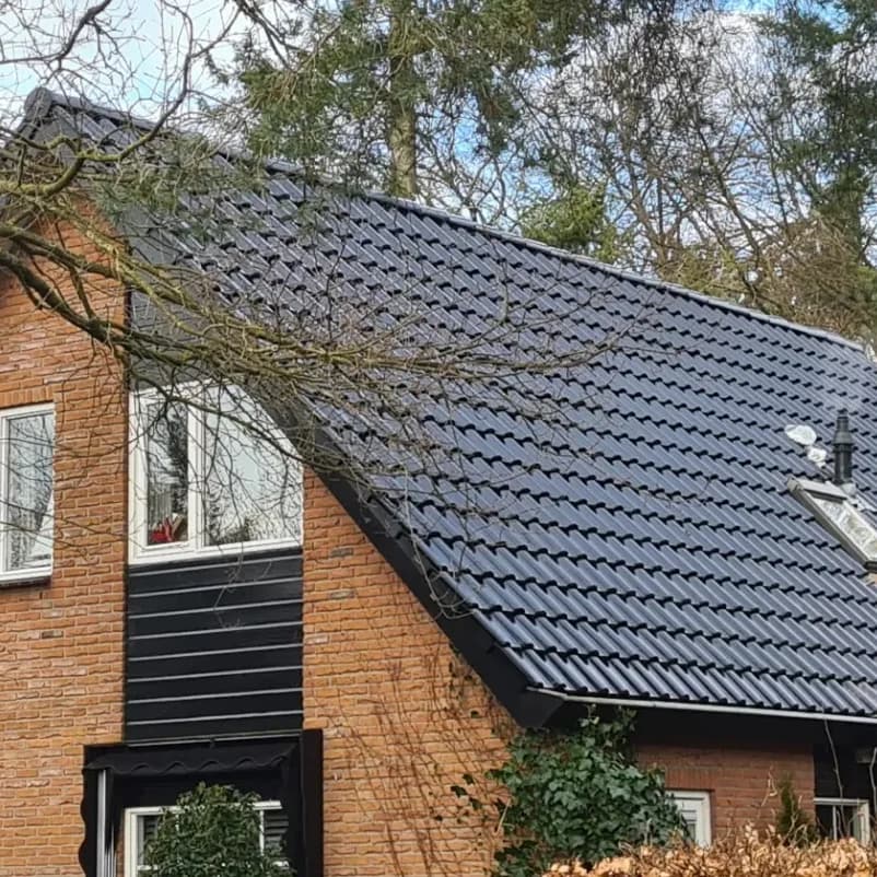 Hetzelfde woonhuis met een nieuw zwart pannendak, strak gelegd tot aan de nok.