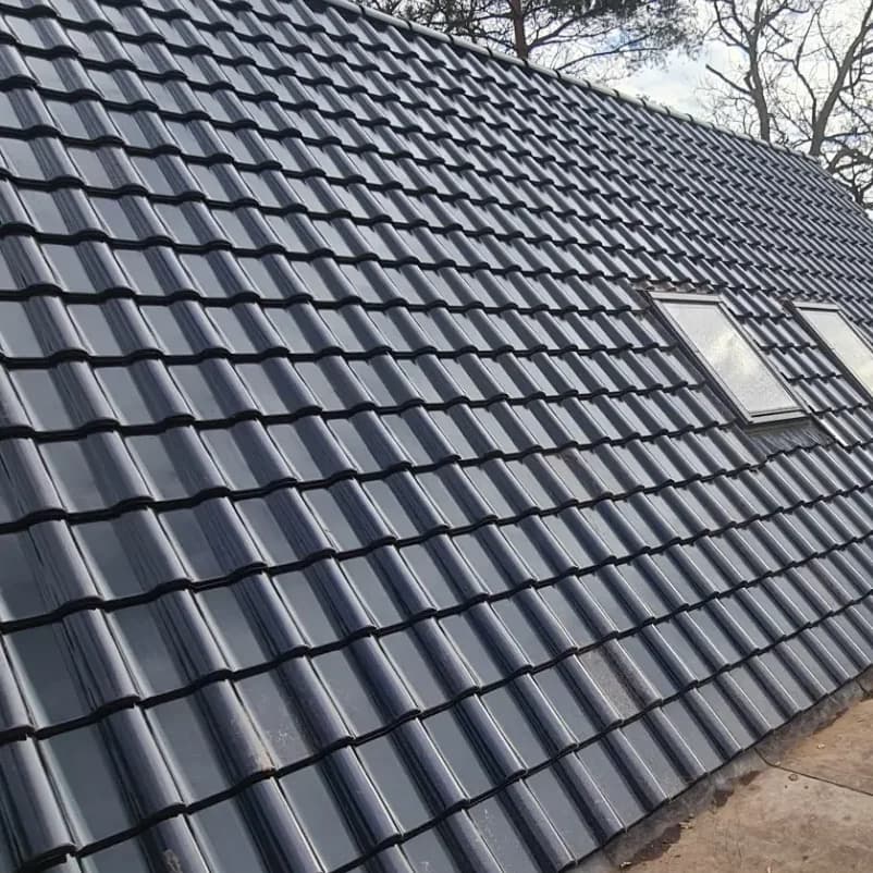 Hetzelfde dakvlak met nieuwe antracietkleurige dakpannen en twee schone dakramen.